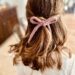 Picture of the back of a brown haired girls hair with a pink crocheted hair bow accessorizing her hair.