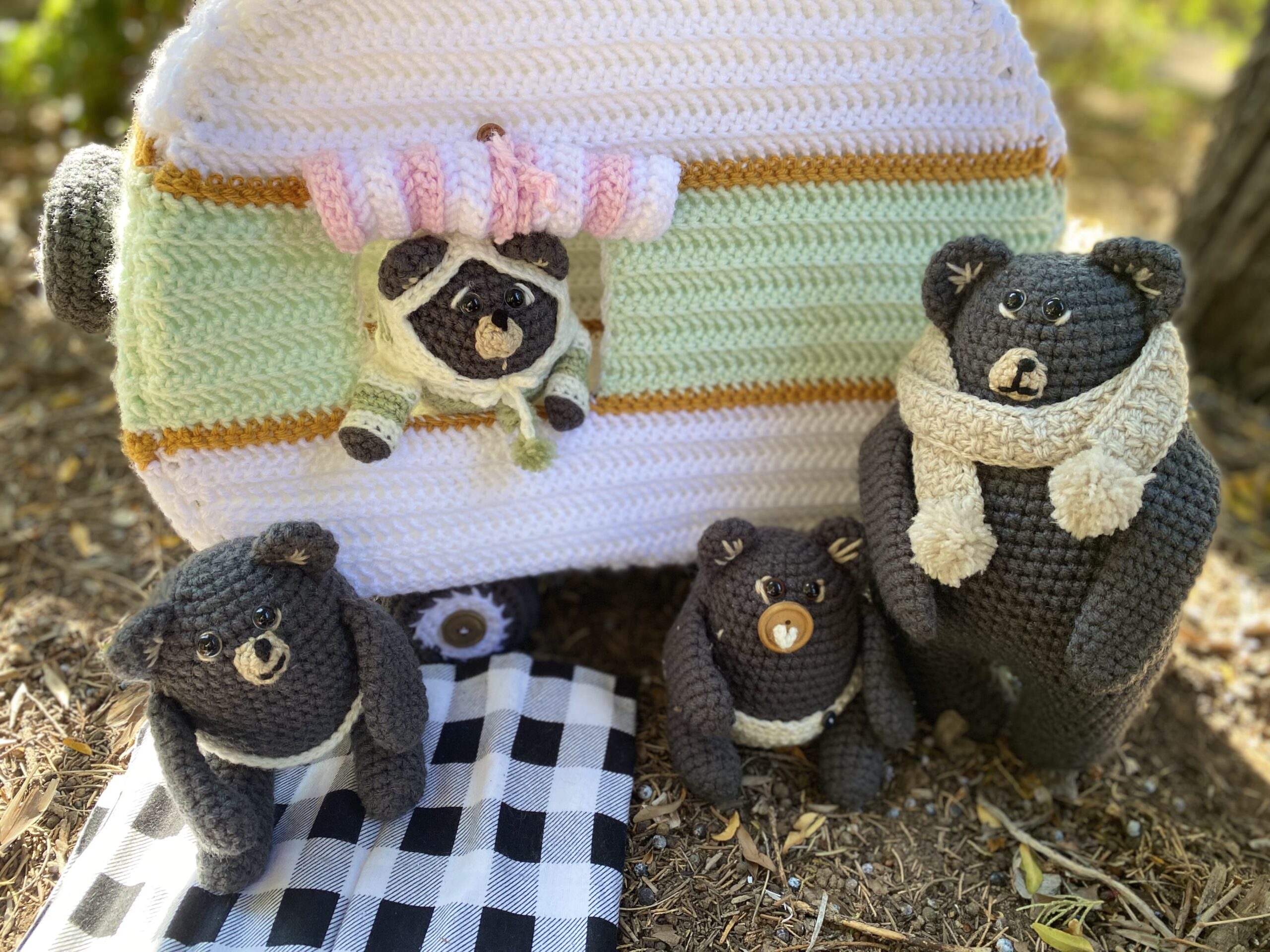 A bear family is going camping in a crocheted camper van in the woods.