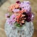 A beautiful January Flower arrangement made of Lavender, Peach and Eggplant Poms.