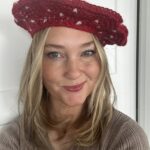 Blonde girl wearing the Be Mine Beret. A red crocheted beret with hearts.